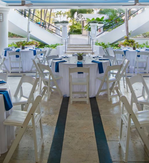 A white and blue banquet room featuring neatly arranged tables and chairs for an event setting.