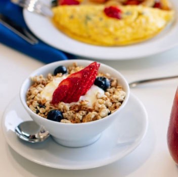 A beautifully arranged hotel breakfast spread featuring fruits, pastries, and beverages on a table.