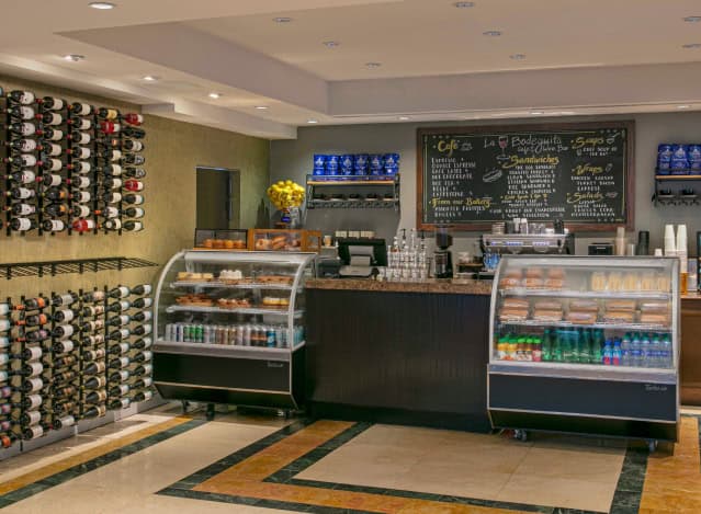 A coffee shop interior featuring a counter and a display showcasing various wine bottles.