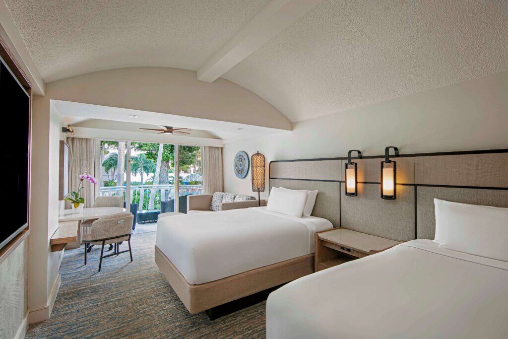 Two beds in a hotel room with a television mounted on the wall, creating a cozy and inviting atmosphere.
