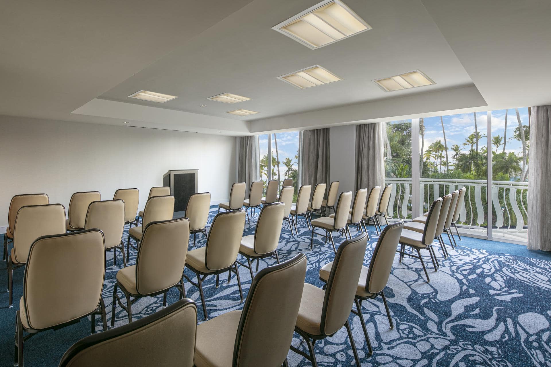 A conference room featuring chairs arranged for a meeting, with large windows showcasing a view of the ocean.