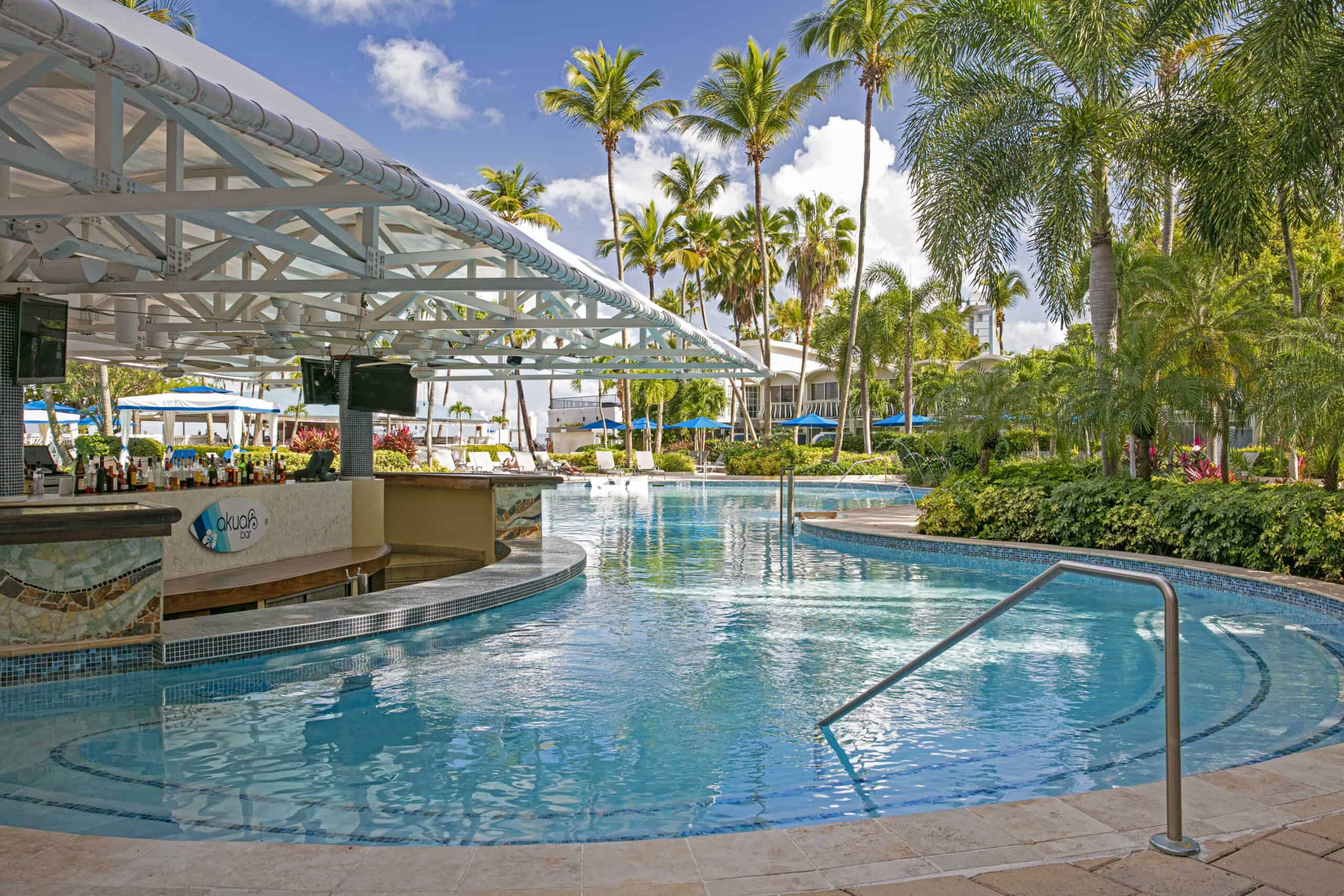 A resort pool surrounded by lush palm trees, creating a tropical and inviting atmosphere for relaxation.