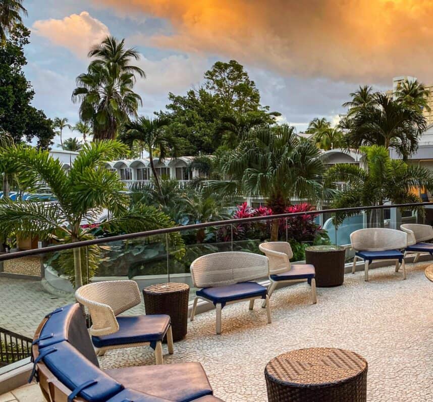 A patio featuring lounge chairs and tables, offering a scenic view of the ocean.
