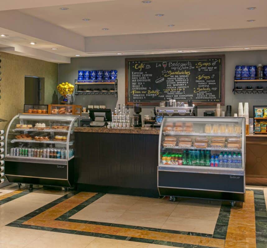 A coffee shop interior featuring a service counter and a glass refrigerator displaying various beverages and snacks.