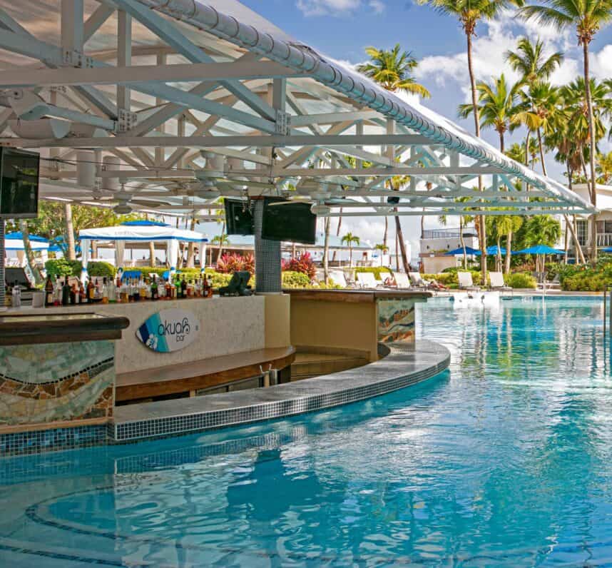 A serene pool area featuring a bar and lounge chairs positioned beside the water for relaxation.