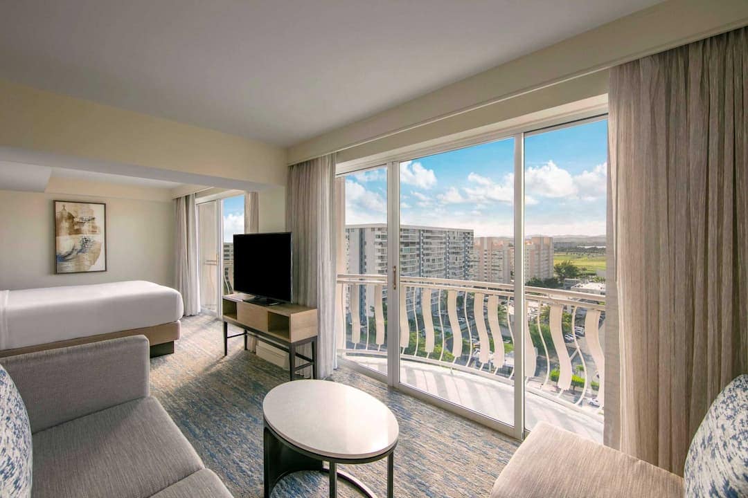A hotel room featuring a large window with a view of the city skyline.