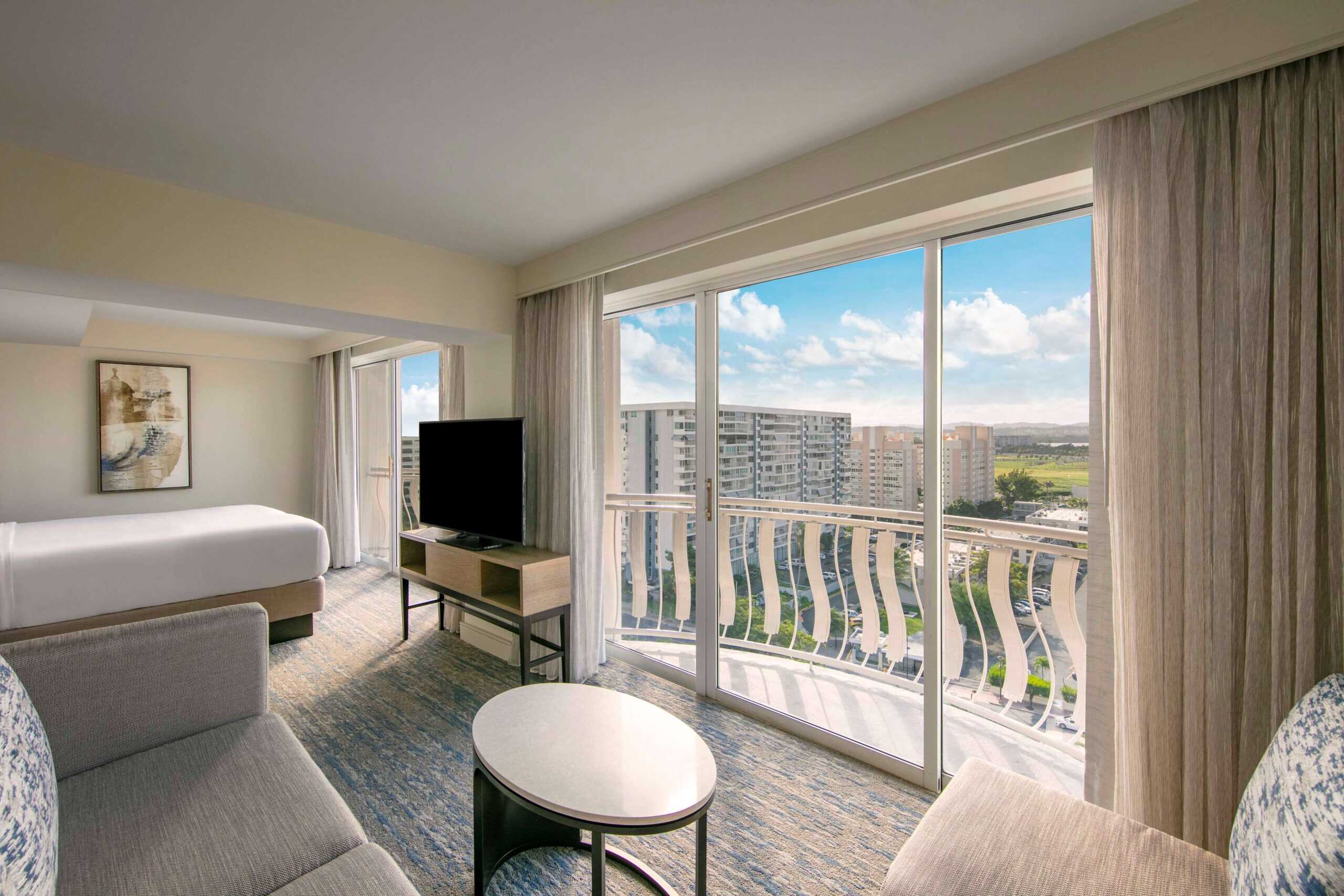 A hotel room featuring a large window with a view of the city skyline.