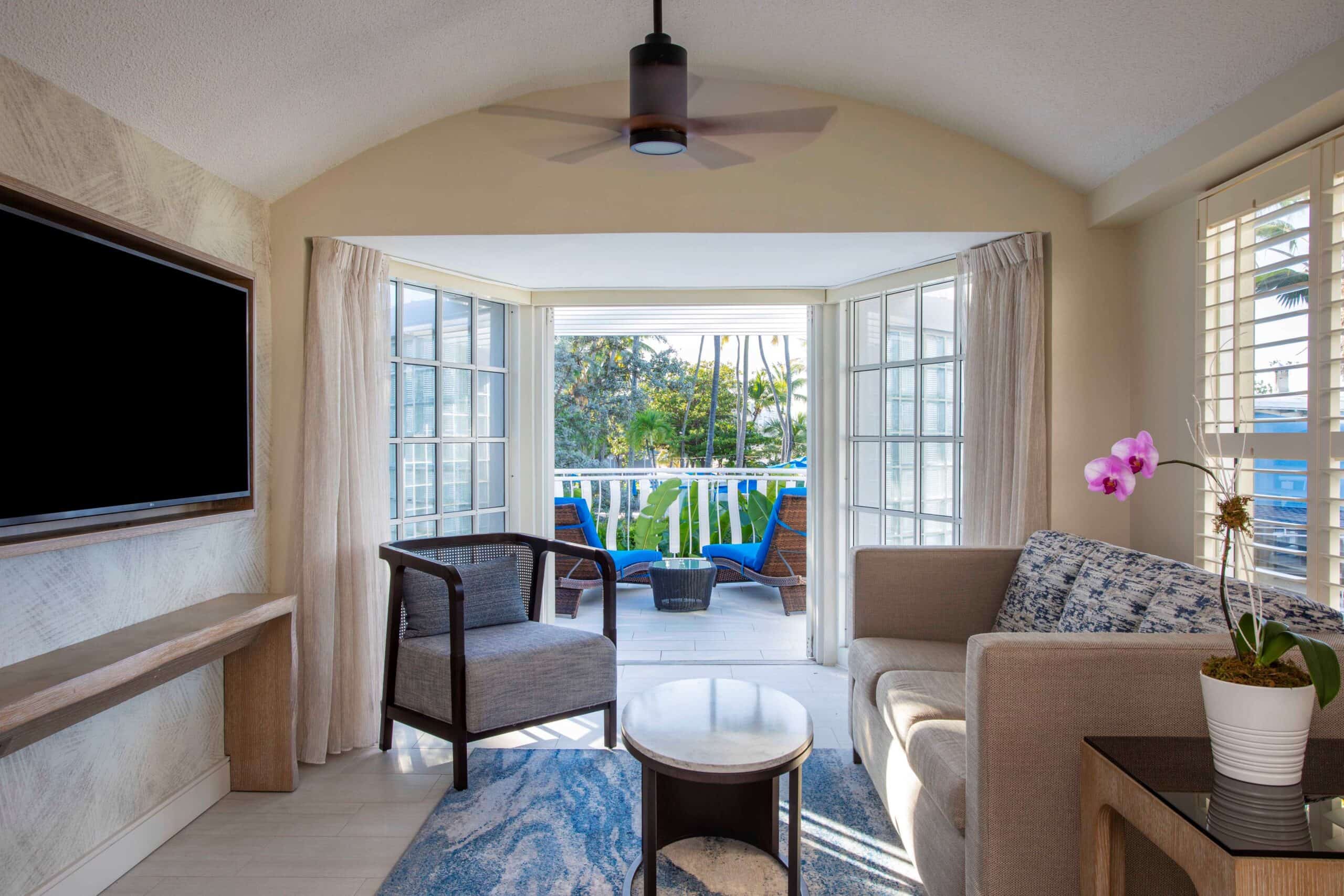 A cozy living room featuring a television and a balcony with natural light streaming in.