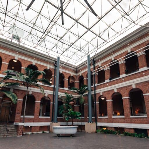 Interior view of a building featuring a spacious area illuminated by a large glass roof overhead.