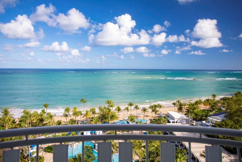 A scenic view of the ocean from a balcony, showcasing waves and a clear blue sky.