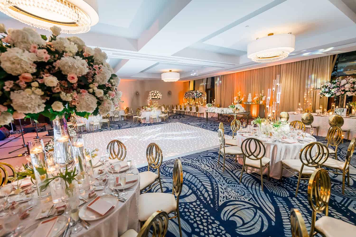 A beautifully arranged wedding reception featuring elegant white and gold decor, creating a sophisticated atmosphere.