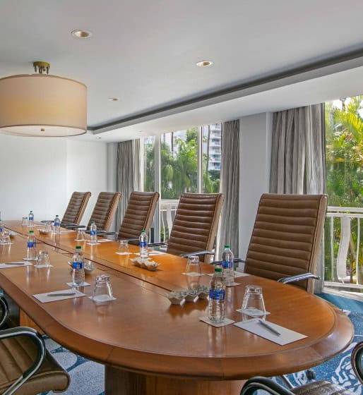 A large conference table surrounded by chairs, with a window providing natural light in the background.