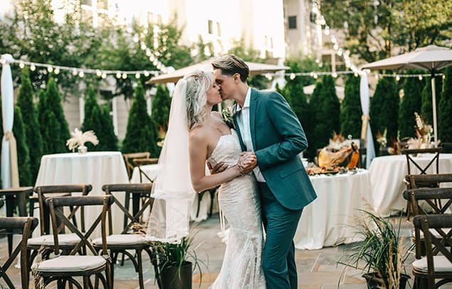 Bride and groom sharing a kiss during an outdoor wedding reception.